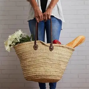 Front view of Moroccan handwoven basket with leather straps on a white background